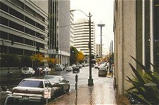 Typical downtown Seattle street scene with rain on sidewalk and Space Needle in the distance.